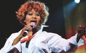 eine Frau in weißer Bluse singt in Mikrofon