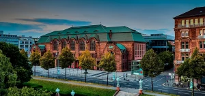 Rosengarten Mannheim – historisches Kongresszentrum mit roter Backsteinfassade und grünem Dach, gelegen an einer mehrspurigen Straße in urbaner Umgebung