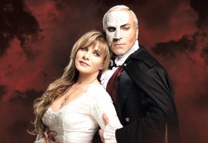 Eine Frau und ein Mann in der Maske stehen vor einem roten Hintergrund