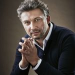 Ein Mann sitzt und hat seine Hände leicht gefaltet