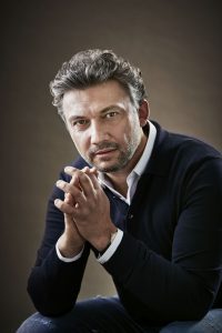 Ein Mann sitzt und hat seine Hände leicht gefaltet