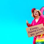 Eine Frau mit einer Tasche mit Regenbogenfarben und einem Schild