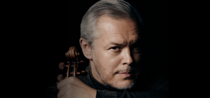 Ein Gesicht eines Mannes vor einem dunklen Hintergrund mit einer Violine an seiner Seite
