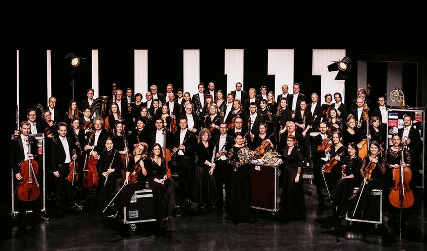 Ein Orchester, gut gekleidet und vor schwarzen Hintergrund