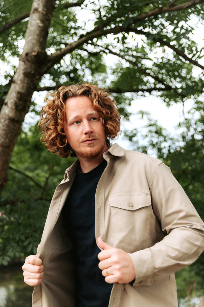 Mann in einer Jacke vor einem Baum