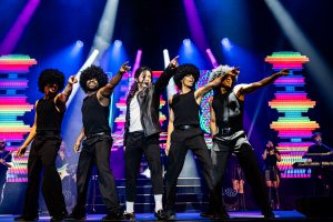 Fünf personen Stehen auf der Bühne mit vielen Farben und Lichter im Hintergrund